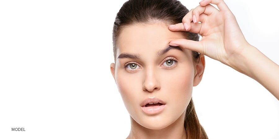 Female squeezing forehead wrinkles with fingers | robert frank md